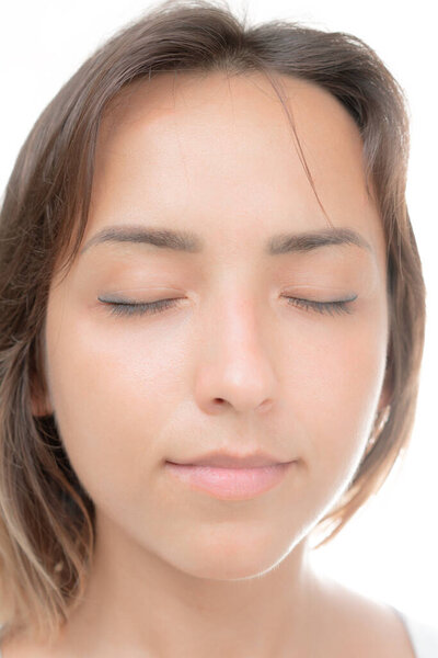 Молодая красивая брюнетка с закрытыми глазами и легкой улыбкой на белом фоне