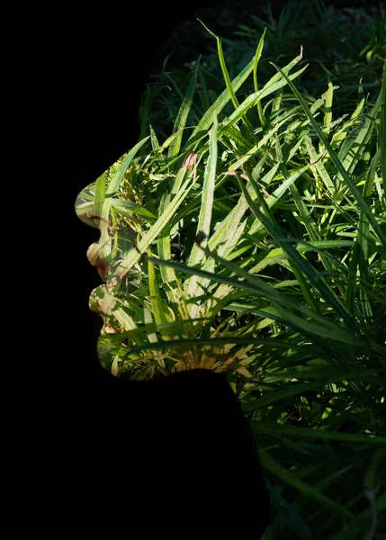 Um retrato de dupla exposição de um perfil de mulheres jovens contra fundo preto e folhagem verde — Fotografia de Stock