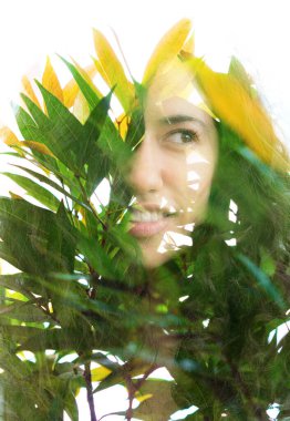 Yarı gülümseyen genç bir kadın portresi ve yeşillik.