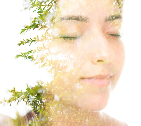 A double exposure portrait of a young beautiful brunette with her eyes closed and branches with little green leaves — Stock Photo, Image