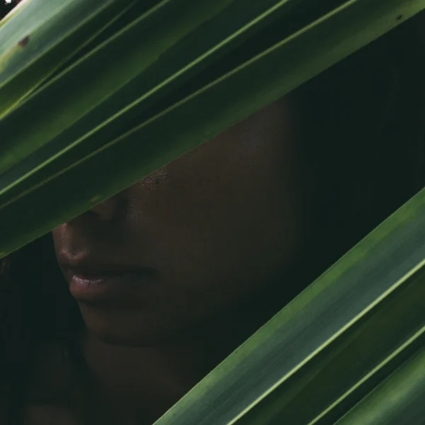 Vrouw verborgen achter palmbladeren — Stockfoto