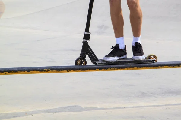 スケートパークのメタルランプの端に沿ってスタントキックスクーターのスライドに乗って — ストック写真