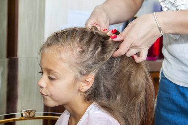 Anne kızının saçını tarar ve evde örer.