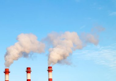 Termik santralde sigara içilen sanayi yığınları mavi gökyüzündeki atmosfere kirli hava yayar.