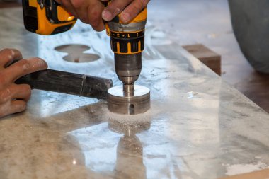 Tamirci, el matkabıyla mutfak için mermer tezgahta elektrik prizleri için yuvarlak delikler açtı.