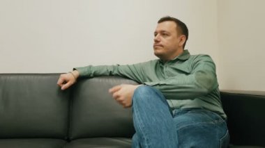 Tarafsız bakışlı bir adam oturur ve saate bakar. Müdür siyah koltukta bekliyor.