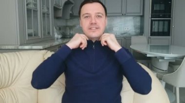 Evdeki kanepede oturan ve kameraya bakan genç bir adam canlı video konferans görüşmesi, video sohbet konsepti yapıyor.