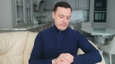 Huysuz ofis çalışanı mutfakta oturur, saate bakar ve perde arkasındaki insanlara seslenir, böylece onun toplantısına müdahale etmezler.