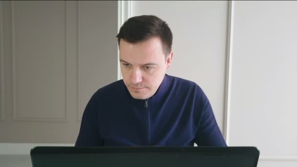 使用笔记本电脑的年轻男性自由职业者坐在家里的写字台前 — 图库视频影像