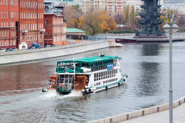 MOSCOW, RUSSIA - 15 Kasım 2020: Büyük Peter anıtı yakınlarındaki Moskova nehrinde tekerleği olan renkli yeşil ve kırmızı motorlu gemi manzarası