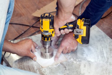 Tamirci, el matkabıyla mutfak için mermer tezgahta elektrik prizleri için yuvarlak delikler açtı.