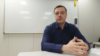 İş adamı beyaz tahtada oturuyor ve online video görüşmesi sırasında toplantı odasında meslektaşlarına sunum yapıyor.