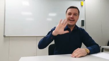 İş adamı beyaz tahtada oturuyor ve online video görüşmesi sırasında toplantı odasında meslektaşlarına sunum yapıyor.