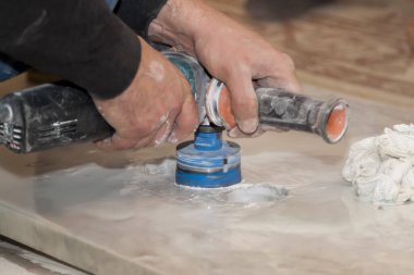 Tamirci elektirik matkabını kullanarak mermer tezgahta elektrik prizleri için yuvarlak delikler açtı.