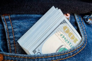 Kotun cebinden çıkan bir tomar 100 dolarlık banknot. Nakit rüşvet kavramı. Kazandığın tüm para krediye verilir..