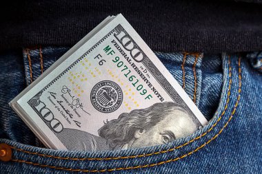 large wad of hundred-dollar bills protrudes from pocket of jeans. Concept of cash bribery. All money earned is all given for credit. clipart
