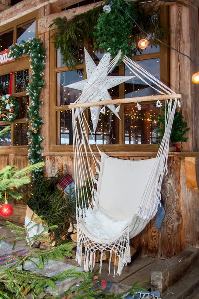 房子的院子里装饰着圣诞节的气氛 圣诞节装饰了家里的阳台 窗户上挂着一颗大白星 冬天的门廊装饰着冷杉树和吊椅 — 图库照片