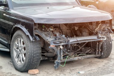Kazadan sonra kaza yapmış arabanın ön görüntüsü. Ön lambaları olmayan parçalanmış araç, tamponsuz kaput ve araba kazasından sonra motor.