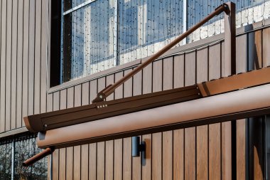 Metal çerçeveli tente ve kahverengi binaya karşı drenaj borusu. ev için modern gölgeleme