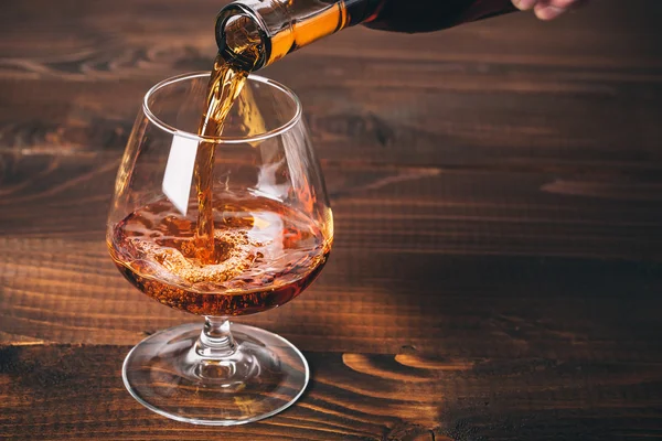 Cognac aus der Flasche gießen — Stockfoto