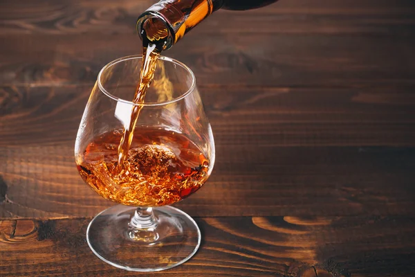 Verser le brandy de la bouteille dans le verre — Photo