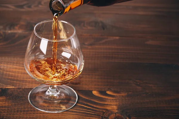 Pouring brandy  from the bottle into the glass — Stock Photo, Image