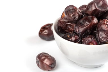 Beyaz arka planda, kasede kurutulmuş hurmalar. Ramazan Kareem kutsal bayram kavramı