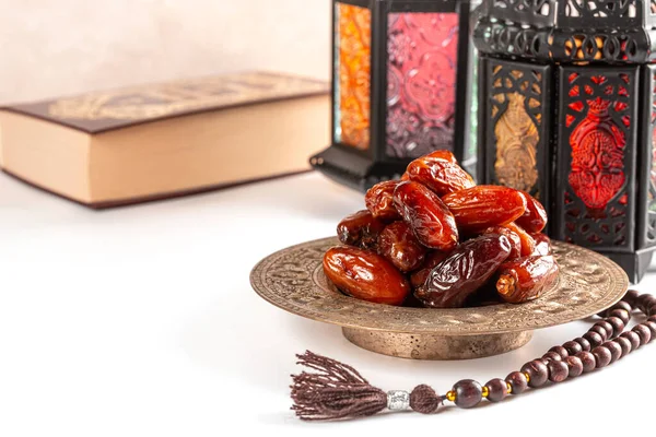 Muslim holiday of the holy month of Ramadan Kareem. Beautiful background with shining lantern, dried dates, prayer beads and quran book