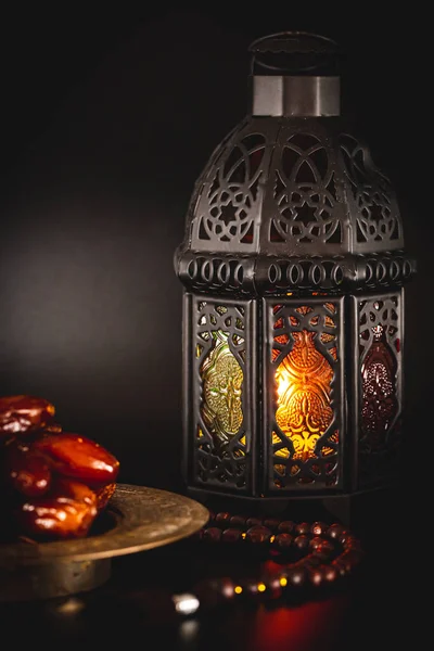 Muslim holiday of the holy month of Ramadan Kareem. Beautiful background with a shining lantern, dried dates on black background
