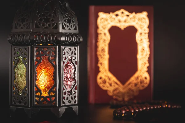 Muslim holiday of the holy month of Ramadan Karim on a dark background with a background with a shining lantern and a book of the Koran