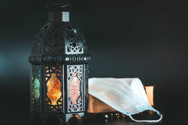 穆斯林节日斋月卡里姆在黑暗的背景下与闪亮的灯笼和一本书可兰经与医疗面具 庆祝斋月在检疫 流行病 大肠癌流行或Covid 19概念 — 图库照片