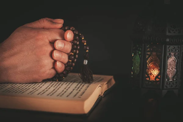イスラム教の聖書 コーラン を明るい提灯で黒の背景で祈る男の手 ラマダーンカレーム聖月のお祝いのコンセプト — ストック写真