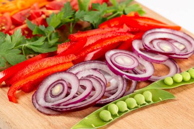 Beyaz arka planda dilimlenmiş sebzelerle ahşap tahtaya yakın çekim, sağlıklı gıda kavramı