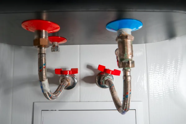 Dos tuberías de agua flexibles para agua fría y caliente conectadas a la caldera doméstica en el baño —  Fotos de Stock