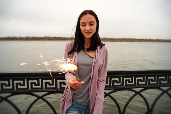 Young woman on embankment with sparkler — Stock Photo, Image