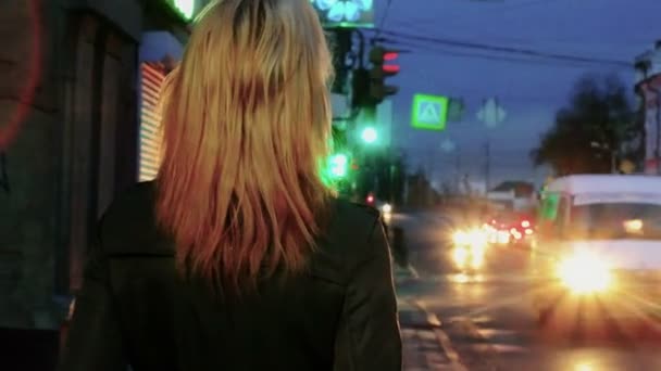 Young blond haired woman in nights street looking back toned shot — Stok video