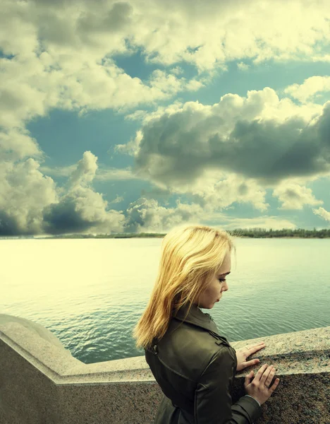 Pensive nő támaszkodva gránit tenger-fal Ander ég felhők — Stock Fotó