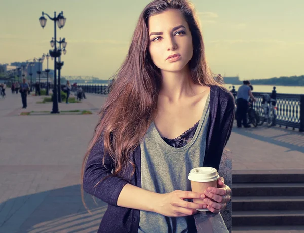 Beautiful young woman with hot drink in disposable paper cup, takeaway coffe in hands, with copy space. — Stock Fotó