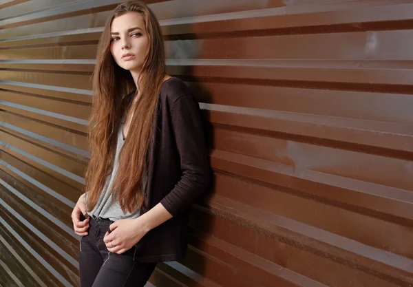 Menina bonita Pensive olhando para a câmera encostada à cerca de metal com bandas paralelas. Menina jovem hipster vestida com roupas legais desfrutando de belo dia de primavera — Fotografia de Stock