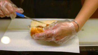 Orta atış garson hazırlanması ve sandwichon kağıt hizmet şeffaf glowes eller