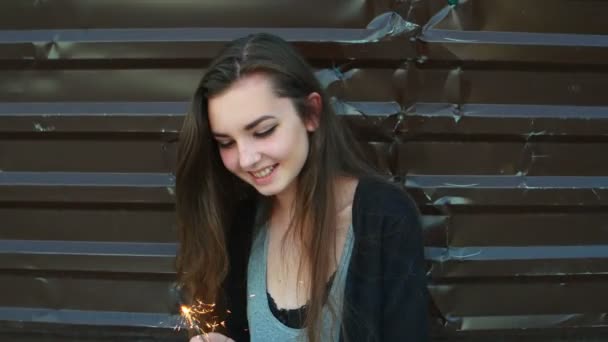 Gelukkig jonge vrouw met sparkler tegen metalen hek in slow motion. — Stockvideo