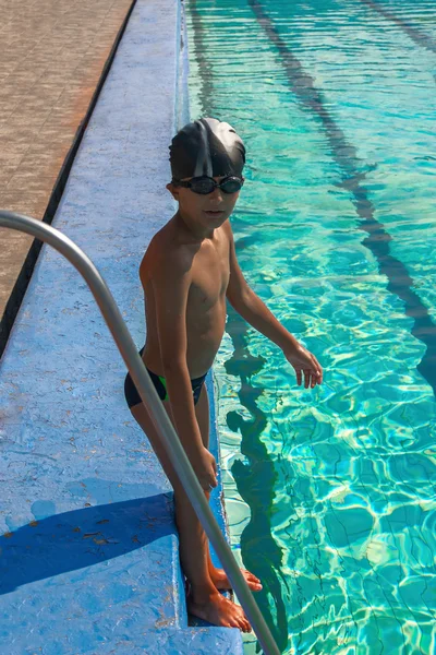 Netter Junge tauchbereit im Sportschwimmbecken, das am Rand nahe der Poolleiter steht — Stockfoto