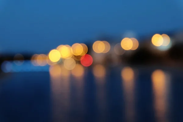 Rozmazané světla měst s bokeh efekt projeví na vodní hladině. — Stock fotografie