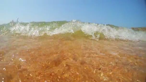 Bajo el agua en un fondo marino poco profundo y la superficie del agua con pequeñas olas rompiendo en la playa de arena — Vídeos de Stock