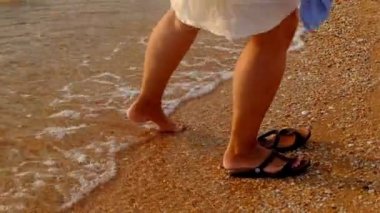 Terlik üzerinde koymak ve vurdu plaj gün batımı steadicam yürüyen kadın