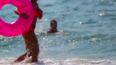 Güzel gün halka lifebuoy tanınmayan insanlar boyunca plaj dalgalar halinde yürüyen kadın