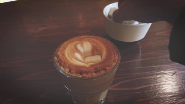 L'uomo aggiunge due pezzi di zucchero al caffè e poi mescola. — Video Stock