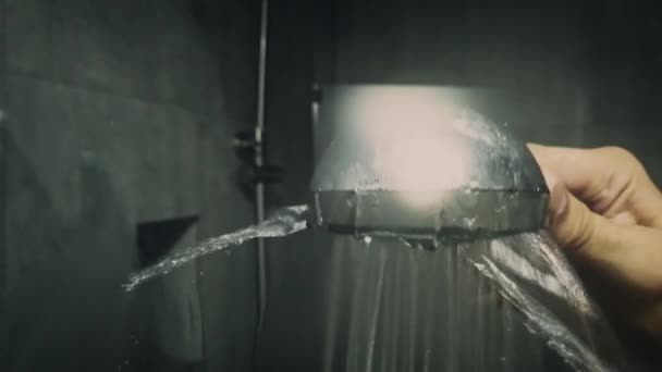 Low light shot of mans hand holding shower head behind the glass of shower cabin — Stock Video