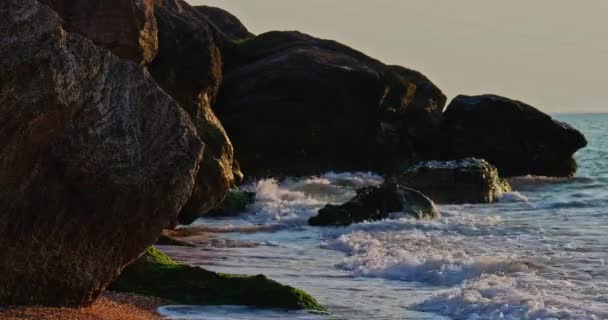 Rochers et vagues s'écrasent contre eux au coucher du soleil — Video