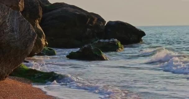 Pan shot of the sea coast with rocks that break sea waves — Stock Video